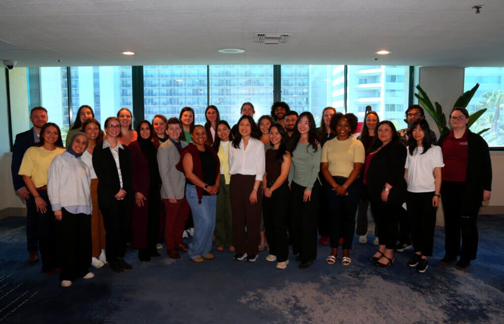 A photo of 30+ student Institute for Future Scientists participants dressed in business casual photographed in a hallway.